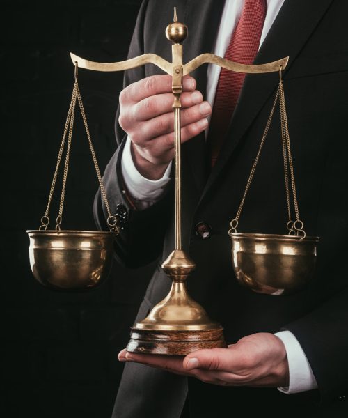 cropped shot of lawyer holding justice scales isolated on black